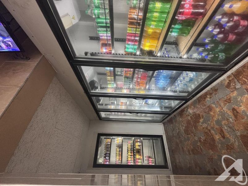Commercial utility area featuring multiple built-in glass-fronted refrigeration units for beverage storage and durable tiled flooring.
