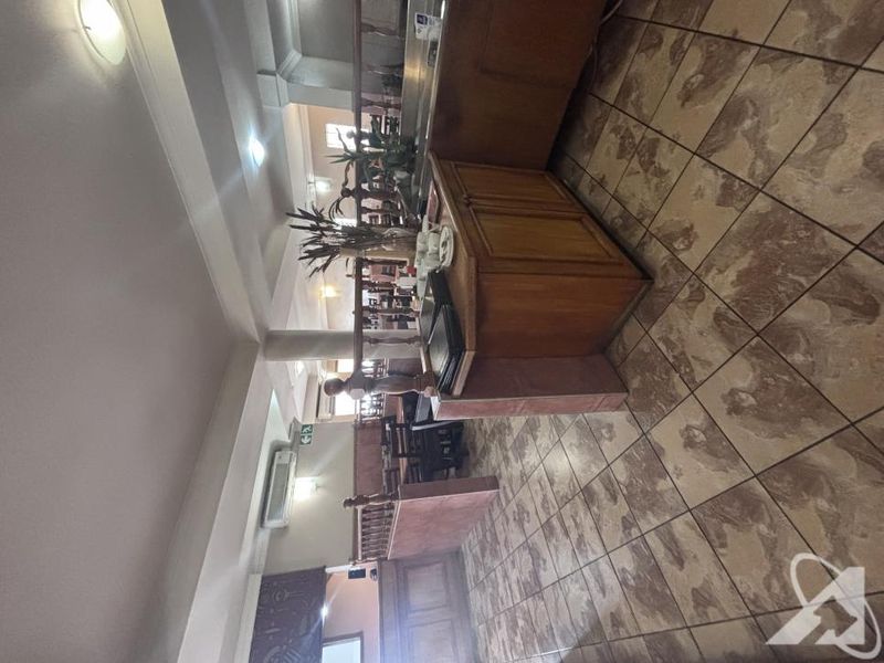 Open plan commercial space featuring built-in wooden cabinetry, ceramic tiled flooring, and a split-system air conditioning unit.