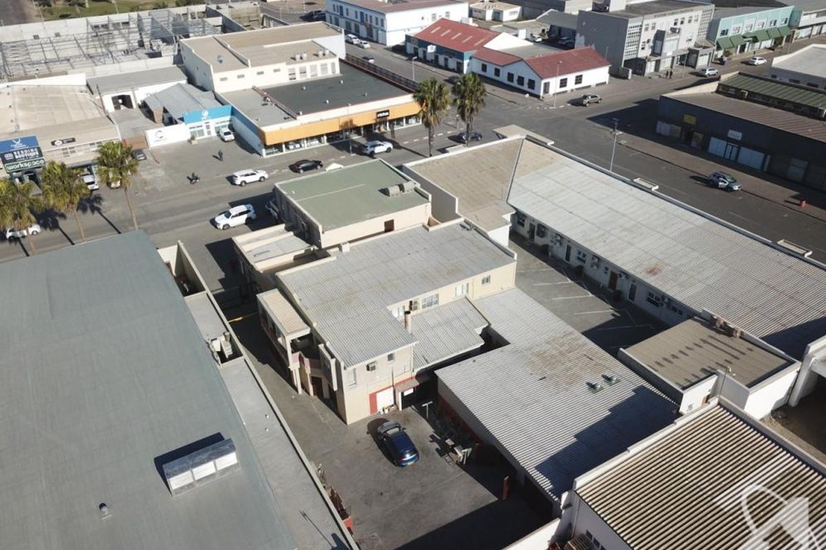 Aerial view of a commercial property complex featuring multiple buildings with corrugated metal roofing and an asphalt parking area.