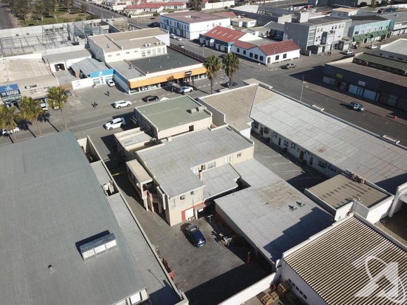 Aerial view of a commercial property complex featuring multiple buildings with corrugated metal roofing and an asphalt parking area.