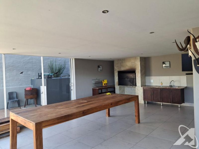 Covered patio area featuring a built-in braai, tiled flooring, recessed lighting, and a built-in kitchenette with sink and cabinetry.