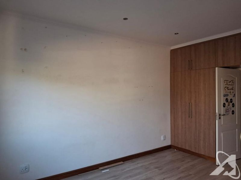 Empty bedroom featuring laminate flooring, built-in wooden cupboards, and recessed ceiling lighting.