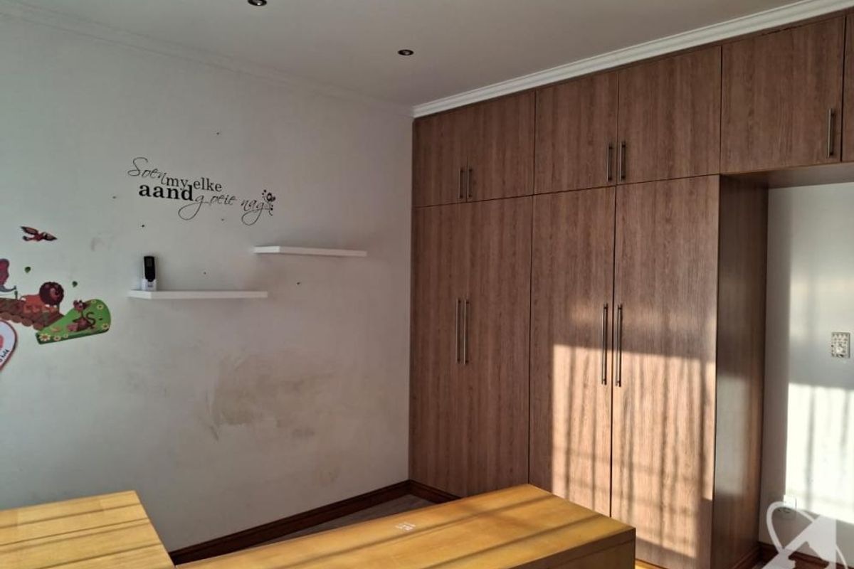 Bedroom featuring extensive floor-to-ceiling built-in wooden cupboards, recessed lighting, and floating shelves, requiring minor wall repairs and cosmetic updates.