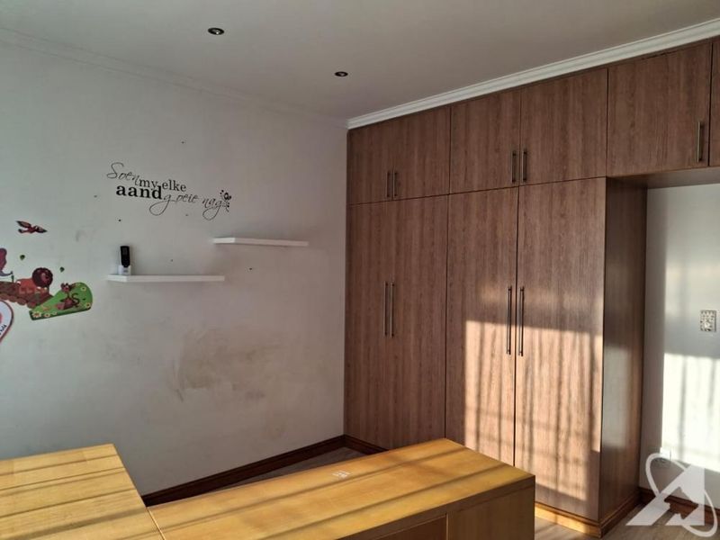 Bedroom featuring extensive floor-to-ceiling built-in wooden cupboards, recessed lighting, and floating shelves, requiring minor wall repairs and cosmetic updates.