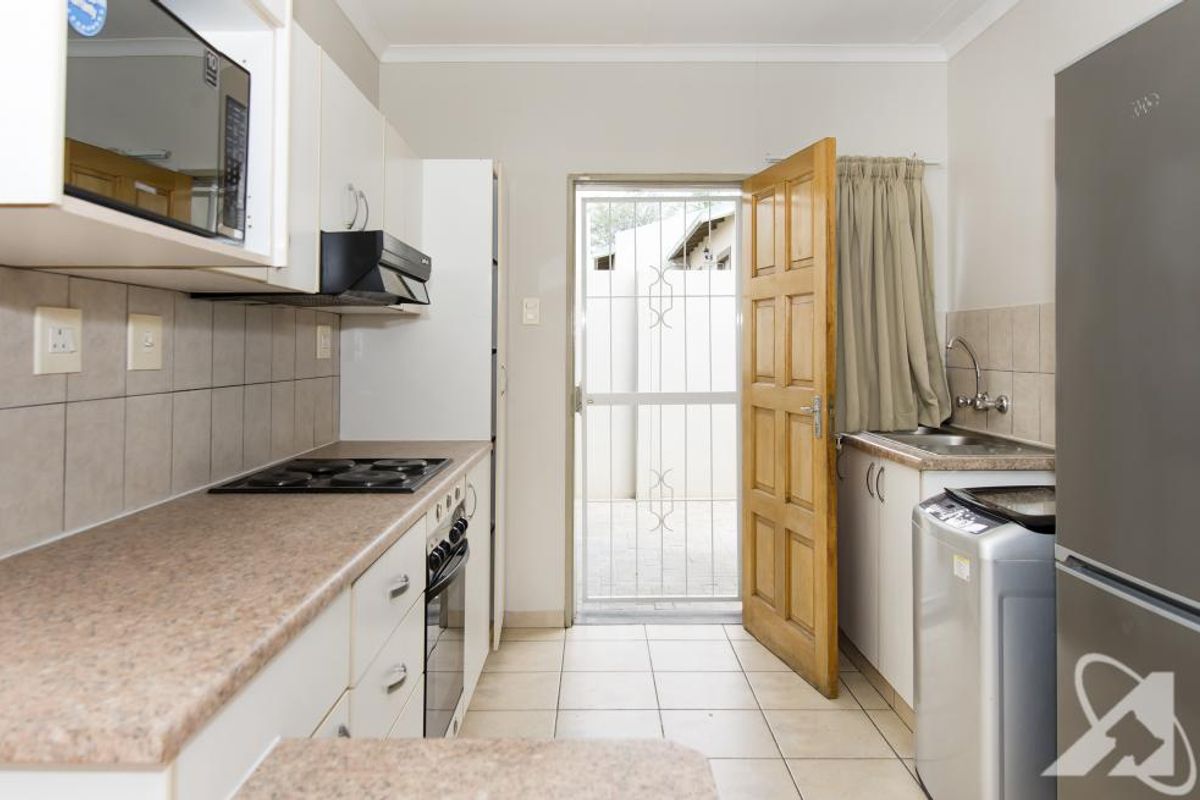 Functional kitchen featuring laminate countertops, built-in oven and hob, extractor fan, and direct access to an exterior courtyard area.