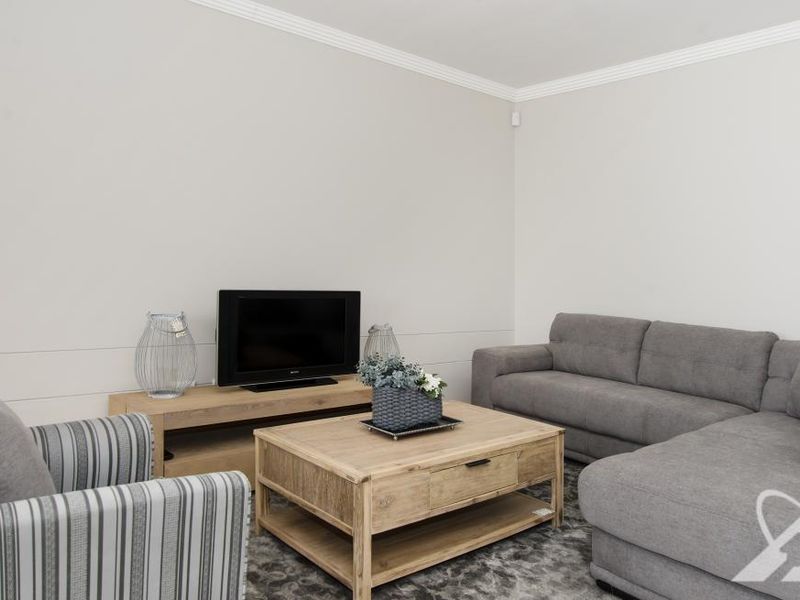 A well-maintained living room featuring neutral wall tones, crown molding, and a security sensor, providing a clean and comfortable space.