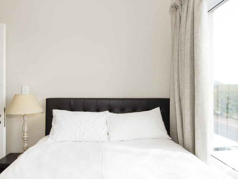 A bright bedroom featuring a large window with natural light and neutral wall finishes.