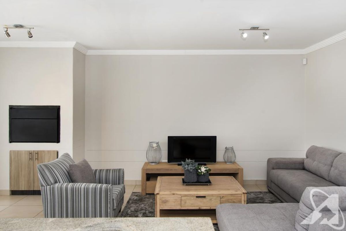 A well-maintained living room featuring neutral walls, crown molding, tiled flooring, and a built-in fireplace with integrated cabinetry.