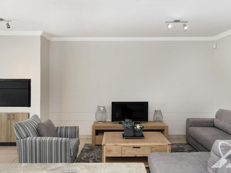 A well-maintained living room featuring neutral walls, crown molding, tiled flooring, and a built-in fireplace with integrated cabinetry.