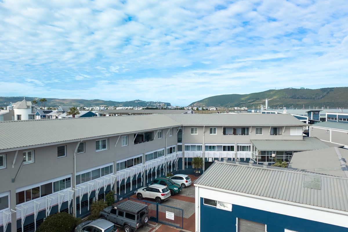 Aerial view of the apartment complex featuring metal roofing, multi-level building facades, and a paved courtyard area with parking.