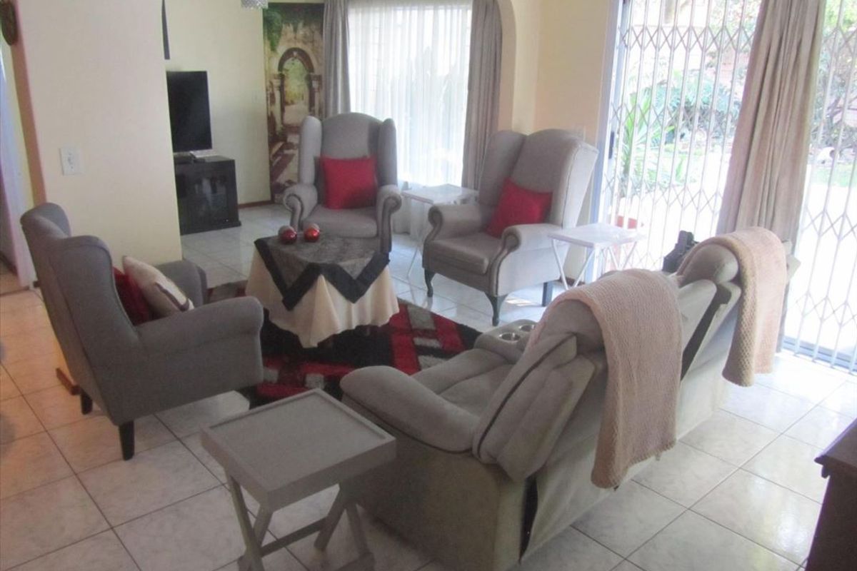 A living room featuring ceramic floor tiles, an arched entryway, and a sliding glass door with a security gate leading to the exterior.