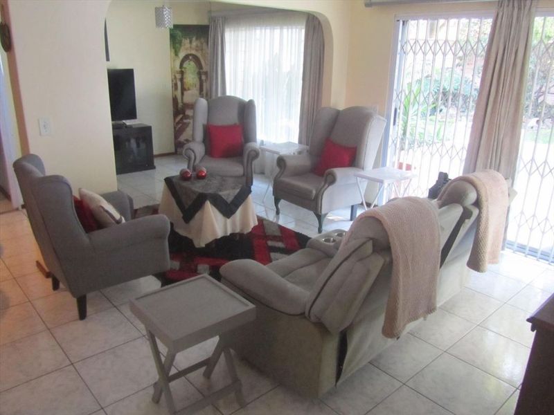 A living room featuring ceramic floor tiles, an arched entryway, and a sliding glass door with a security gate leading to the exterior.