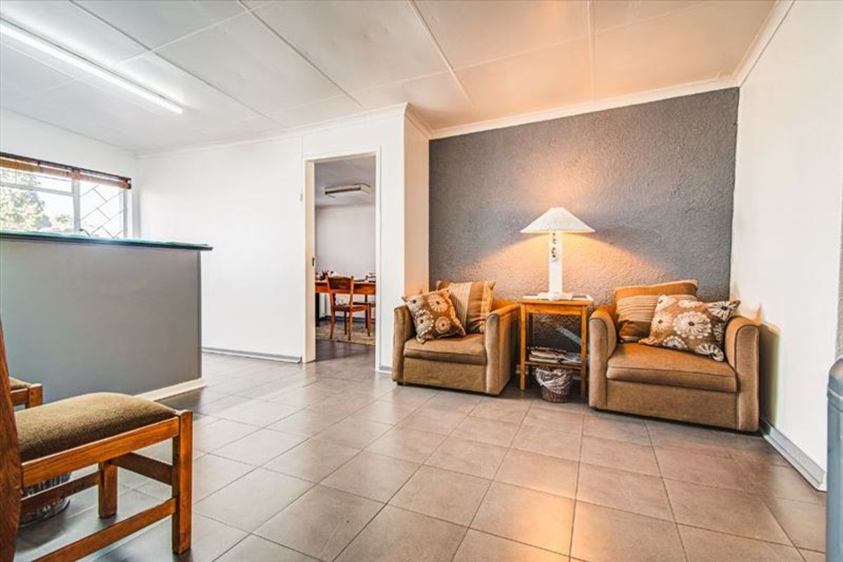 A functional living area featuring tiled flooring, a textured accent wall, and coved ceilings, providing a neutral base for potential interior updates.