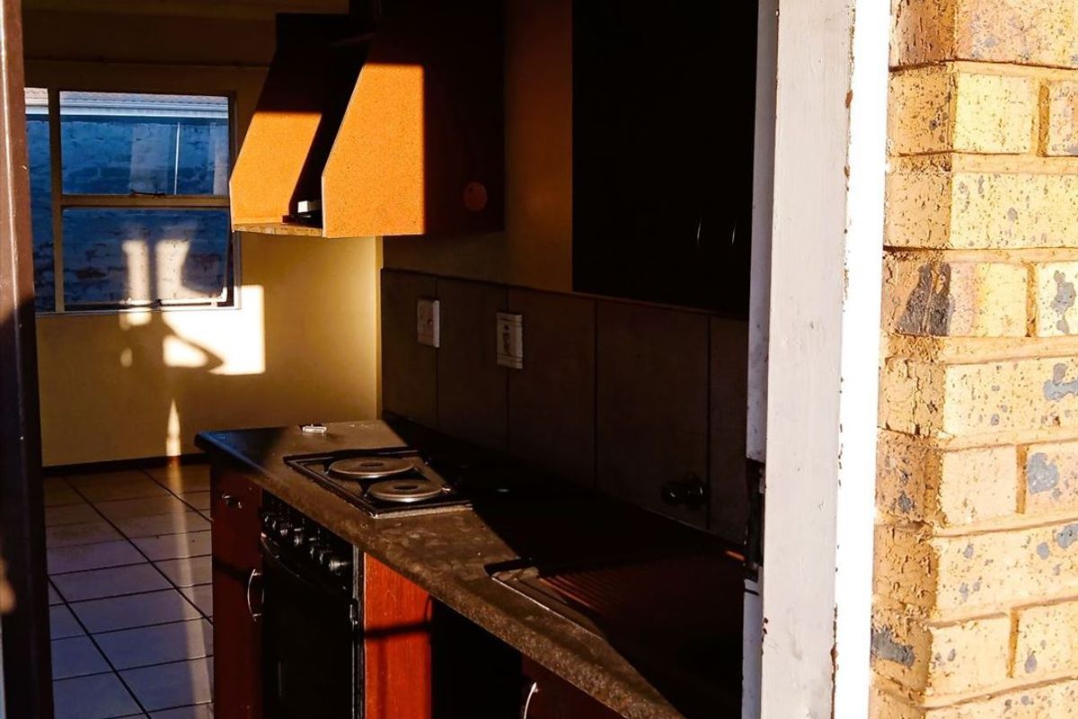 A dated kitchen featuring built-in cabinetry, an integrated oven and hob, and tiled flooring, requiring cosmetic updates to modernize the space.