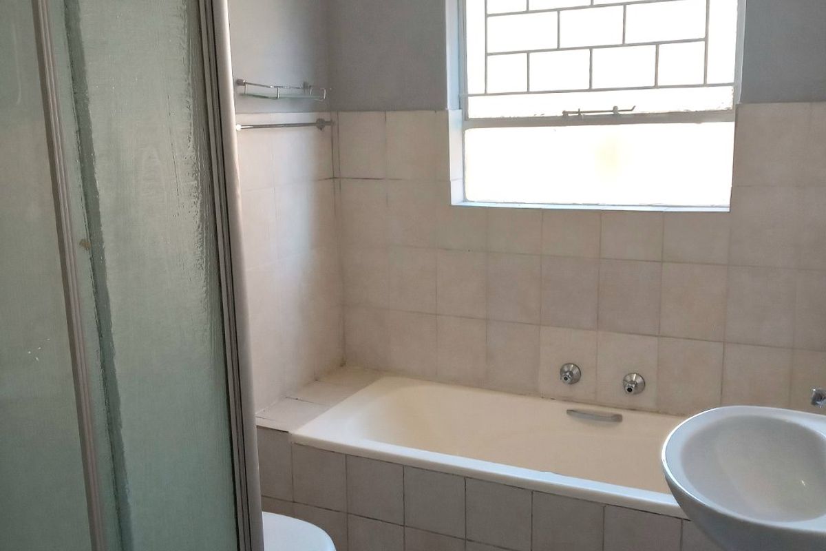 A functional bathroom featuring a shower enclosure, bathtub, pedestal basin, and toilet, finished with tiled walls and flooring.