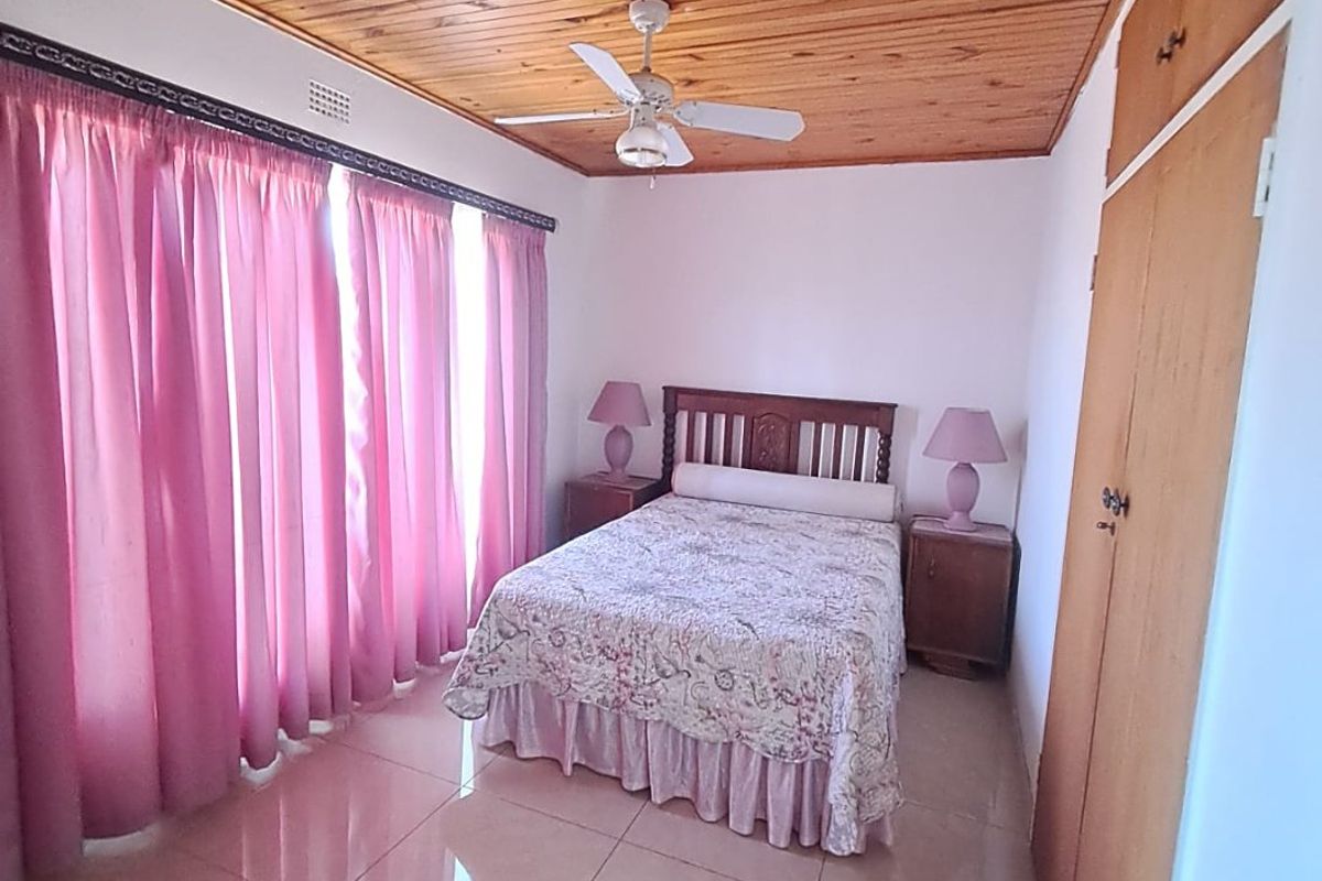 A bedroom featuring a timber-clad ceiling, ceiling fan, tiled flooring, and built-in wooden cupboards.