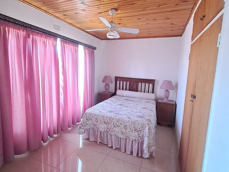 A bedroom featuring a timber-clad ceiling, ceiling fan, tiled flooring, and built-in wooden cupboards.
