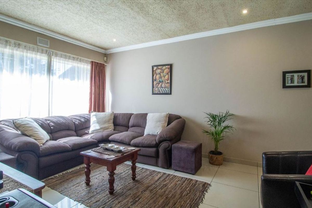 A comfortable living room featuring tiled flooring, textured ceiling, and a large sliding glass door that provides ample natural light.