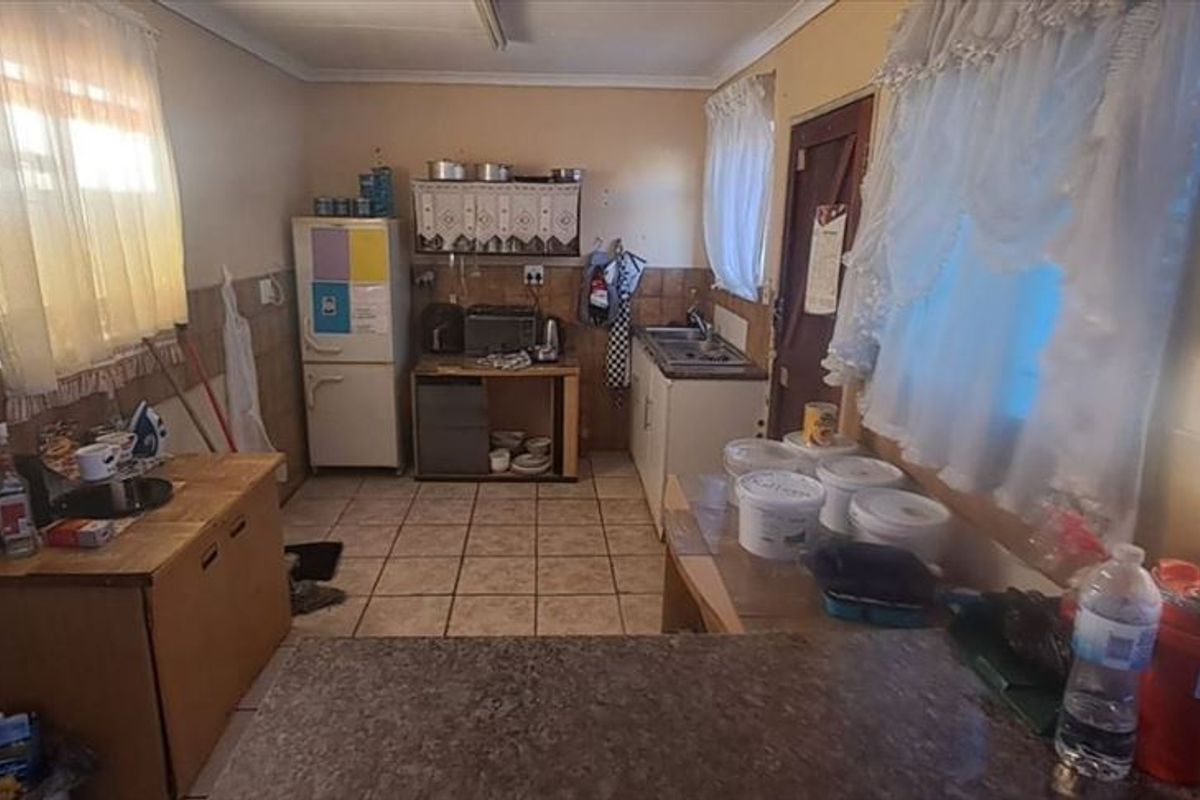 A dated kitchen featuring tiled flooring, tiled splashbacks, and basic built-in cabinetry, offering significant potential for a modern renovation.