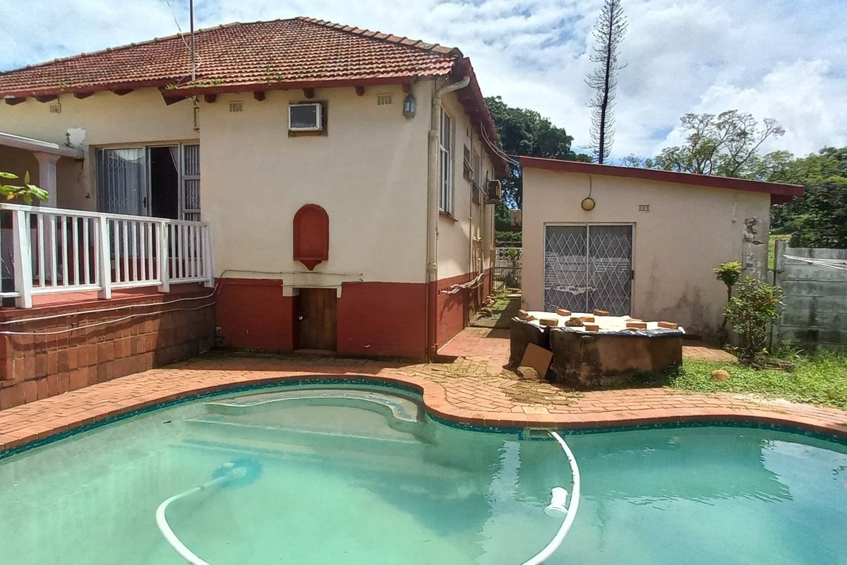 Rear exterior view of the property featuring a swimming pool, raised deck area, and detached outbuilding with a tiled roof.
