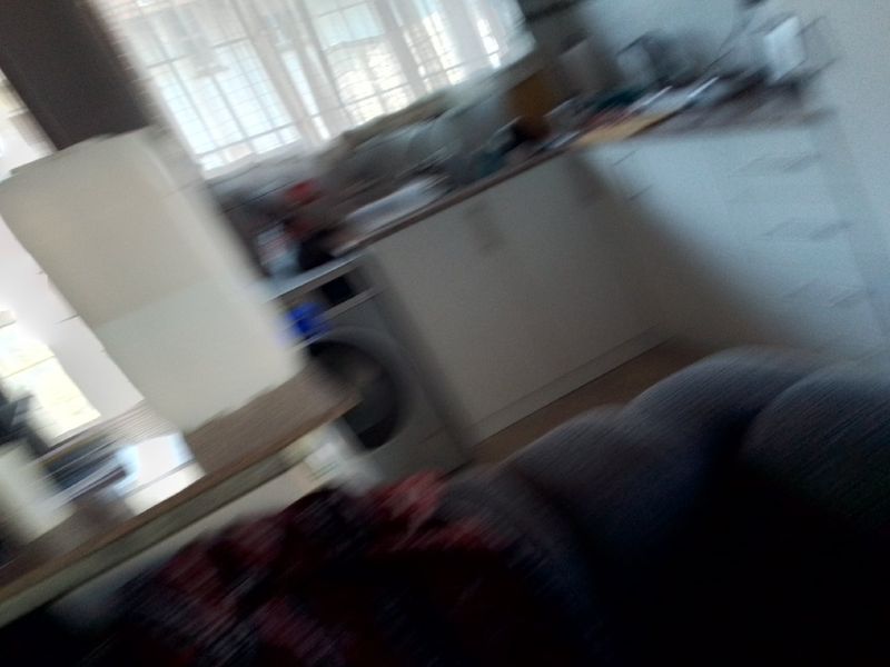 A blurry view of a kitchen area featuring built-in cabinetry, laminate countertops, and an integrated washing machine.