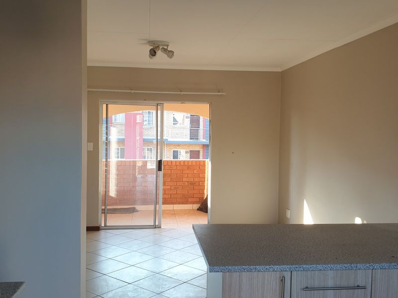 Open plan living area featuring tiled floors, a modern kitchen counter, and a sliding door leading to a private balcony.