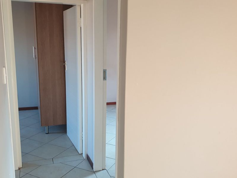 A view through a hallway showing tiled flooring and access to adjacent rooms with built-in cabinetry.