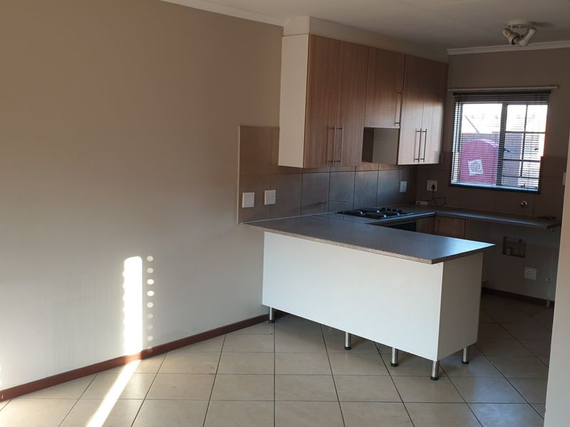 Open plan kitchen featuring built-in cabinetry, laminate countertops, and a gas hob, with tiled flooring throughout the living area.