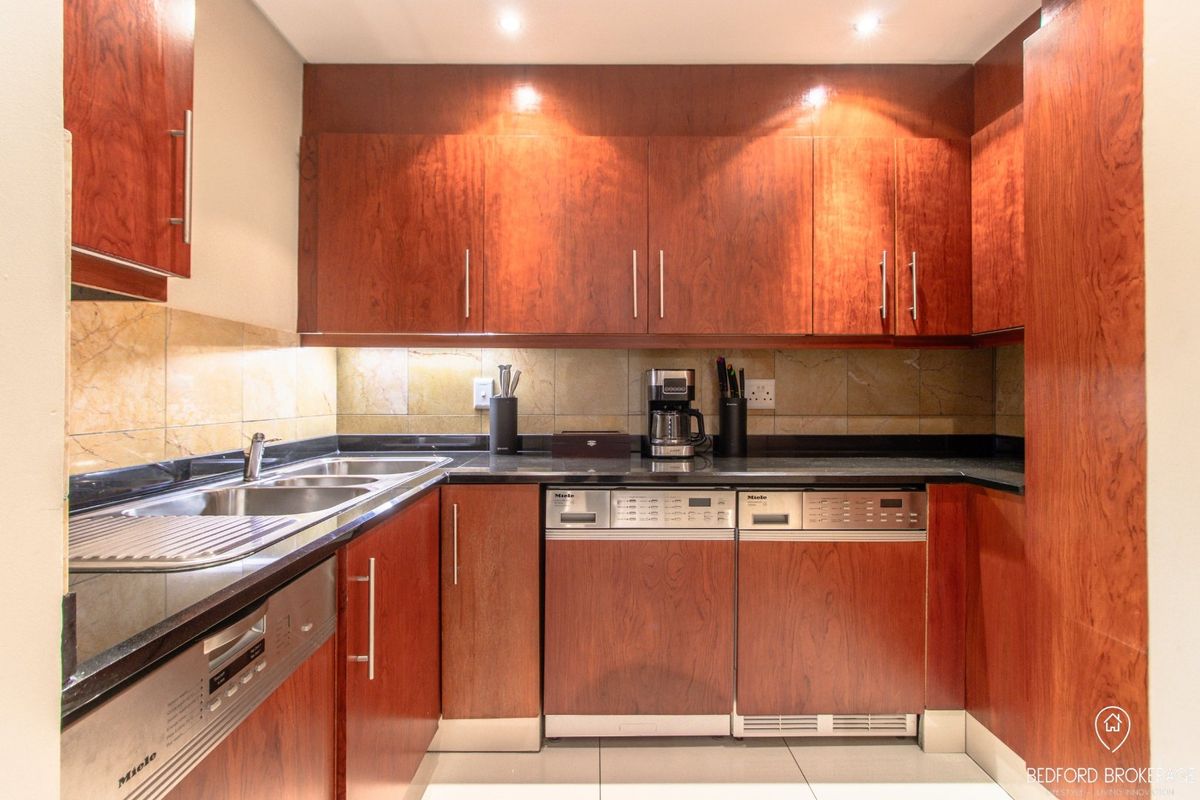 A well-maintained kitchen featuring rich cherry wood cabinetry, granite countertops, integrated appliances, and stone tile backsplash with modern recessed lighting.