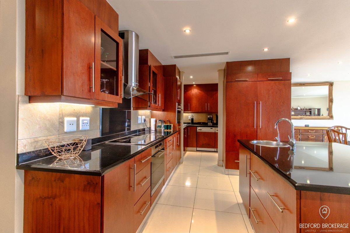 Modern kitchen featuring rich cherry wood cabinetry, sleek granite countertops, integrated appliances, and high-quality porcelain floor tiles with recessed lighting.