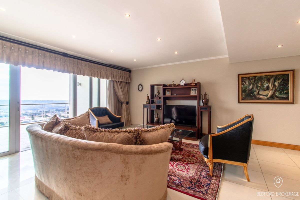 Spacious living room featuring tiled flooring, recessed downlighting, and large sliding glass doors opening to a balcony with expansive views.