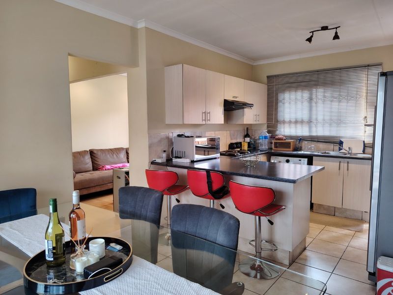 Open-plan kitchen and dining area featuring built-in cabinetry, a breakfast bar, and tiled flooring, with a seamless transition to the adjacent living space.