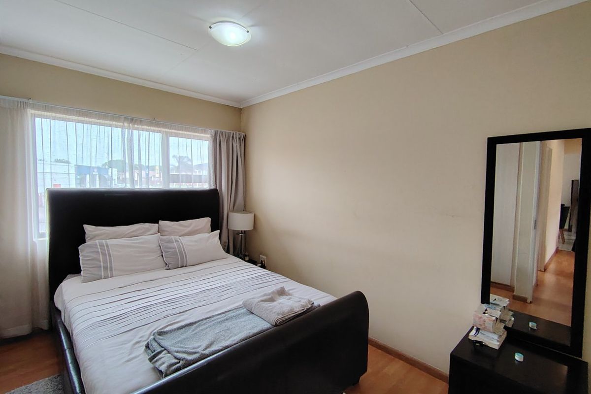 A standard bedroom featuring laminate flooring, a large window for natural light, and neutral wall finishes.