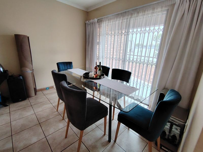 A dining room featuring ceramic tiled flooring and a sliding glass door with a security gate, providing access to the exterior.