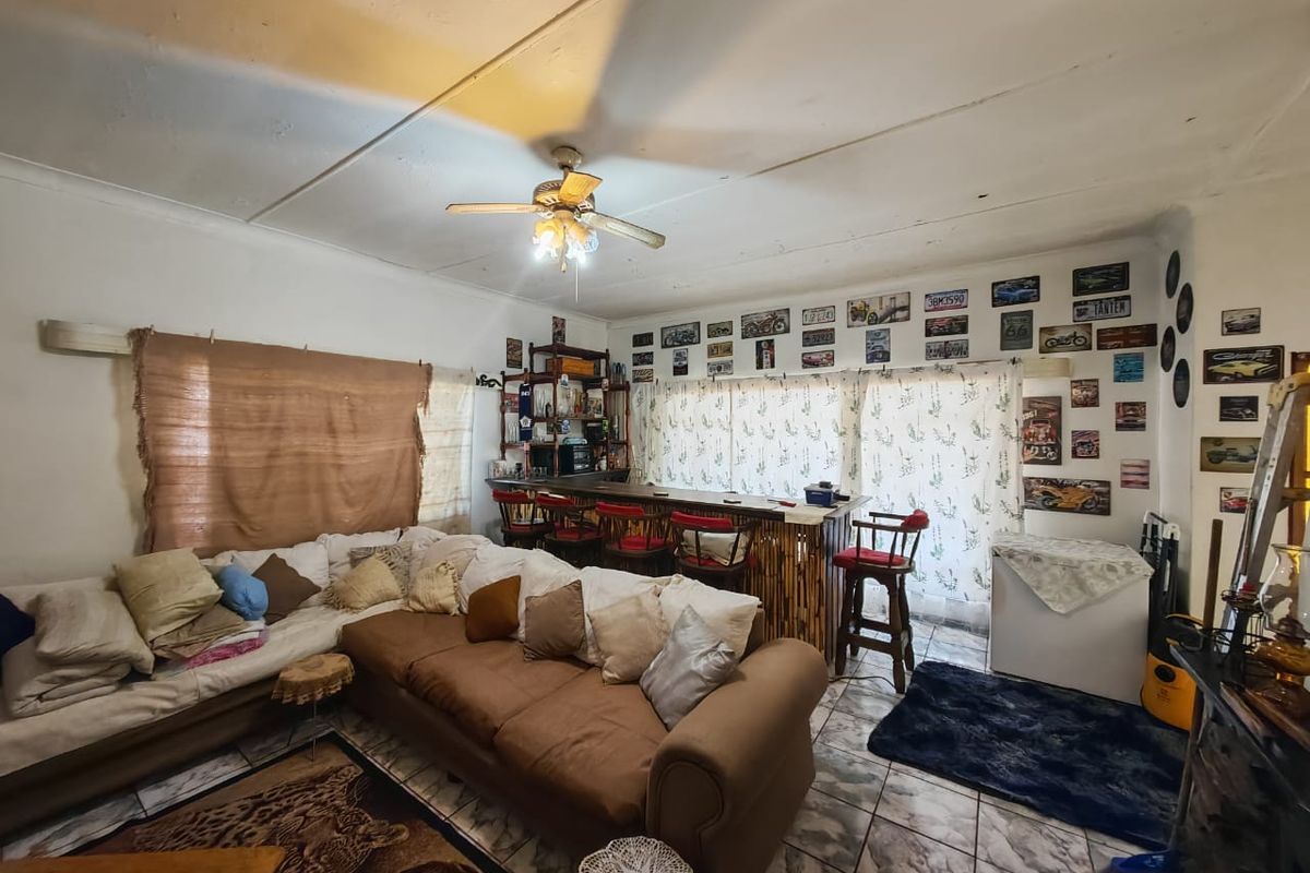 Open plan living area featuring a built-in bar counter, tiled flooring, and a ceiling fan, offering potential for modernization and layout optimization.