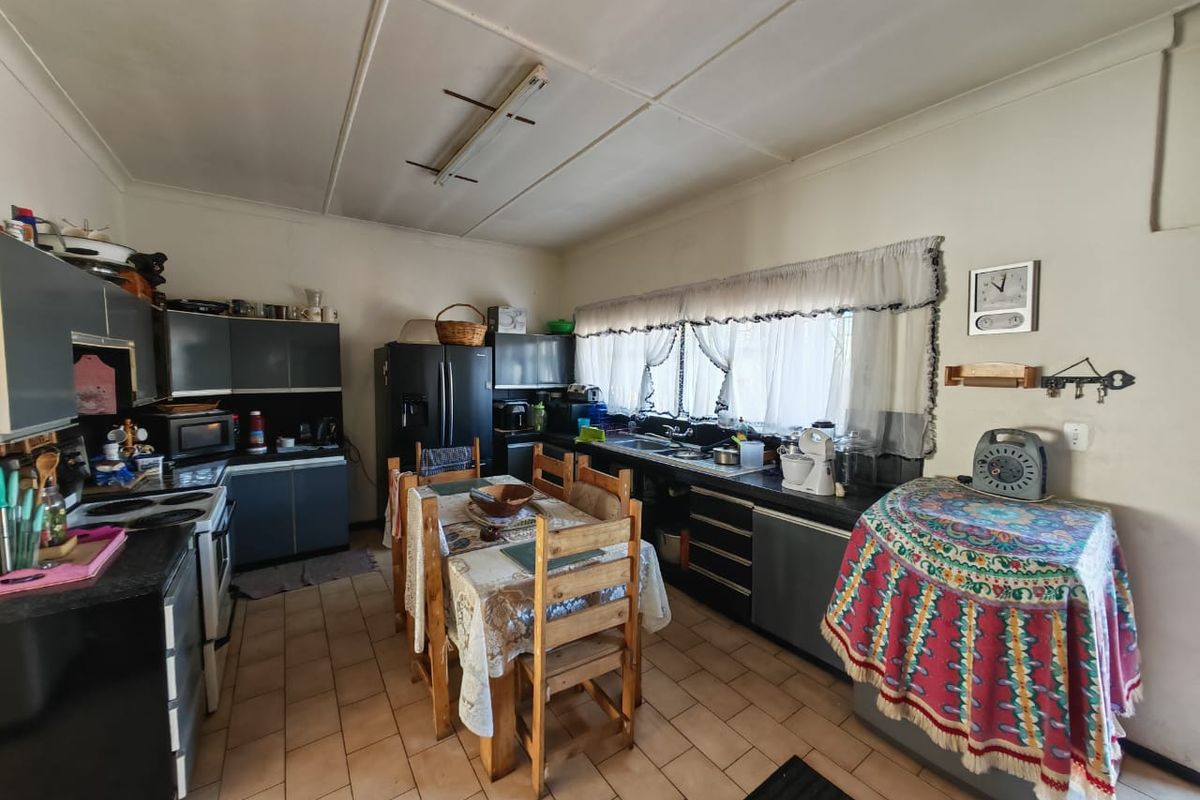 A functional kitchen featuring dark cabinetry, tiled flooring, and a double sink, offering potential for modernization and layout optimization.