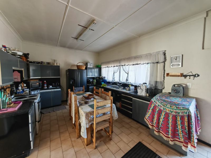 A functional kitchen featuring dark cabinetry, tiled flooring, and a double sink, offering potential for modernization and layout optimization.
