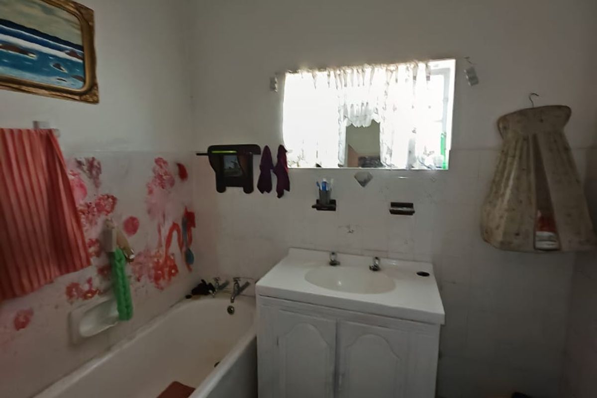 A functional bathroom featuring a built-in vanity with basin and a standard bathtub, currently requiring cosmetic updates to modernize the space.