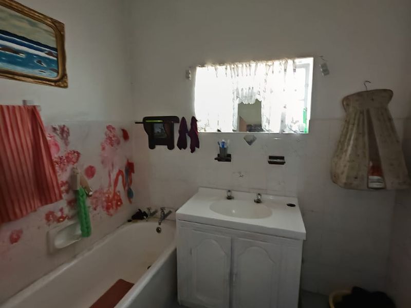 A functional bathroom featuring a built-in vanity with basin and a standard bathtub, currently requiring cosmetic updates to modernize the space.