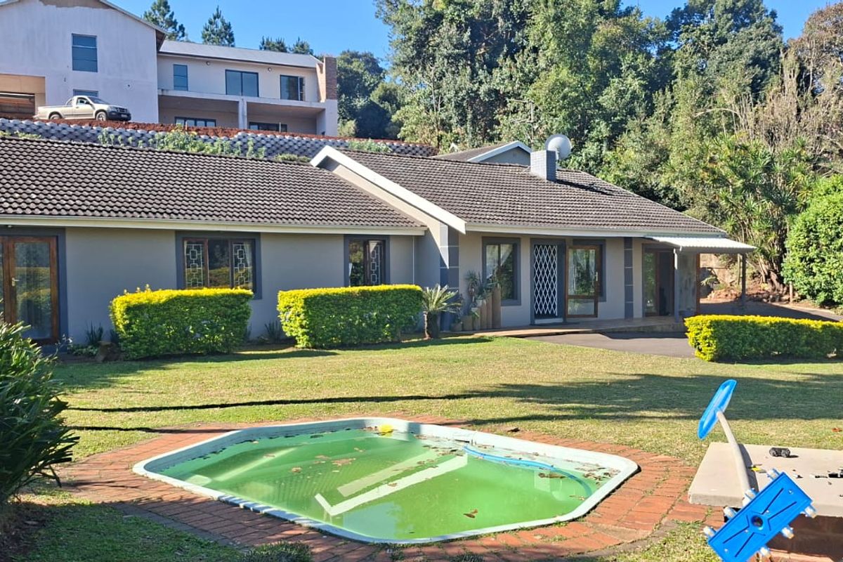 Rear view of the house featuring a lawn, garden, and a swimming pool with brick coping.