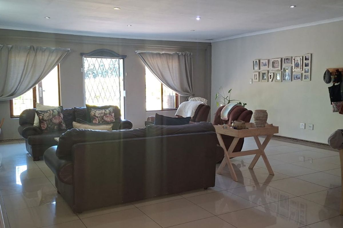 Spacious living room featuring tiled flooring, recessed downlights, and a prominent brick fireplace, offering a comfortable and functional family living space.