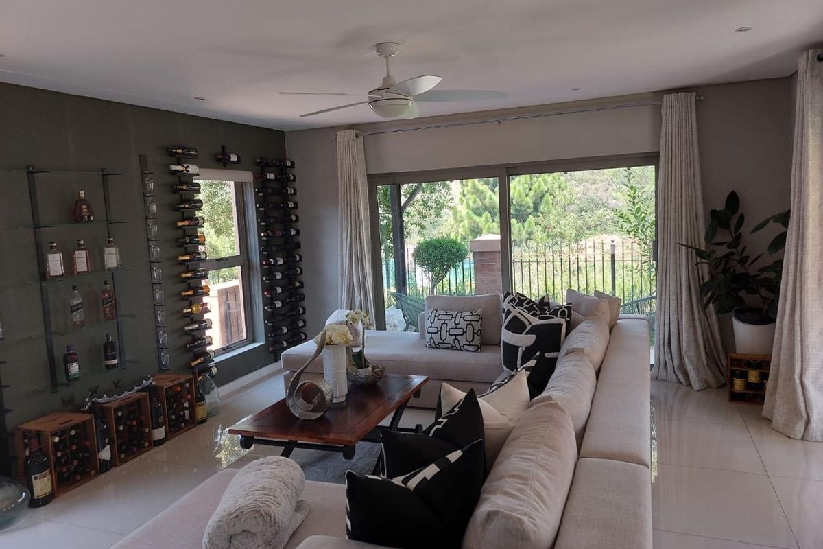 Spacious living room featuring large sliding glass doors, tiled flooring, a ceiling fan, and a custom built-in wine storage wall.