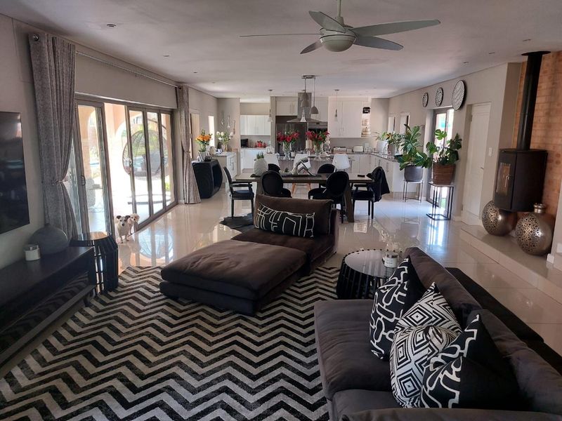 Spacious open-plan living and dining area featuring tiled floors, a modern fireplace, and seamless flow to the outdoor patio through large sliding glass doors.
