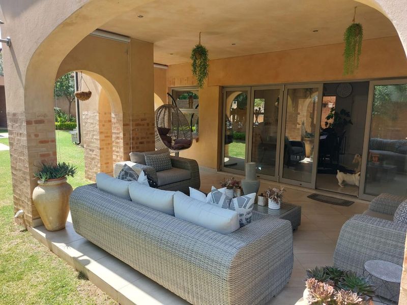 A covered patio area featuring arched masonry columns, exposed brick accents, tiled flooring, and large sliding glass doors providing access to the interior.