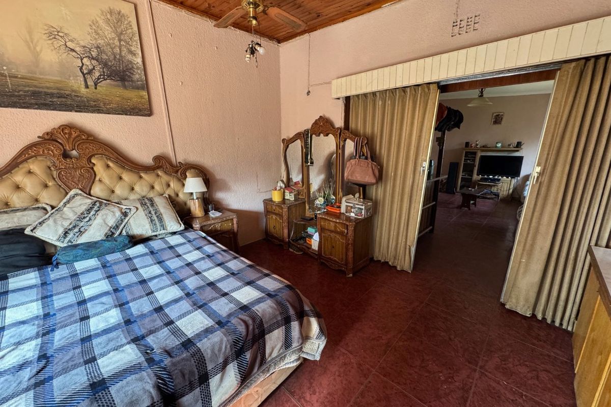A bedroom featuring a wooden ceiling, tiled flooring, and a sliding door partition leading to an adjacent living area.