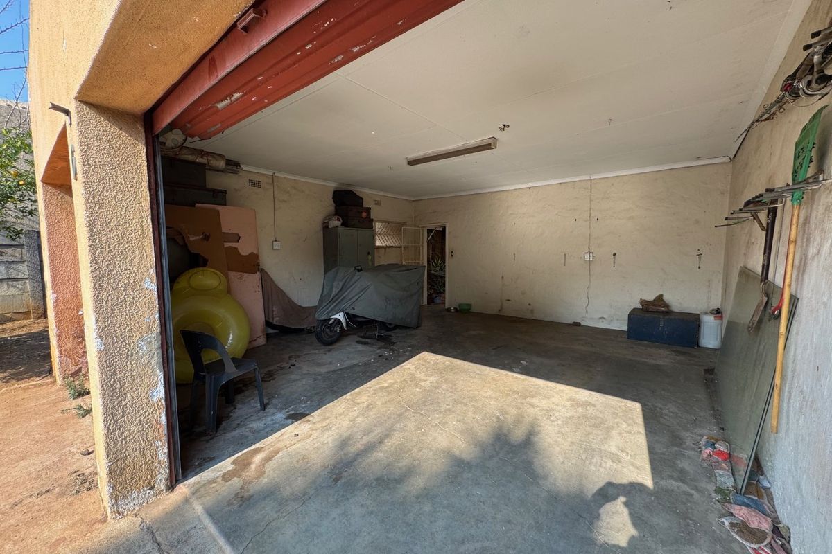 A spacious garage featuring a concrete floor and a roll-up door, requiring maintenance and cosmetic updates to restore its functionality.