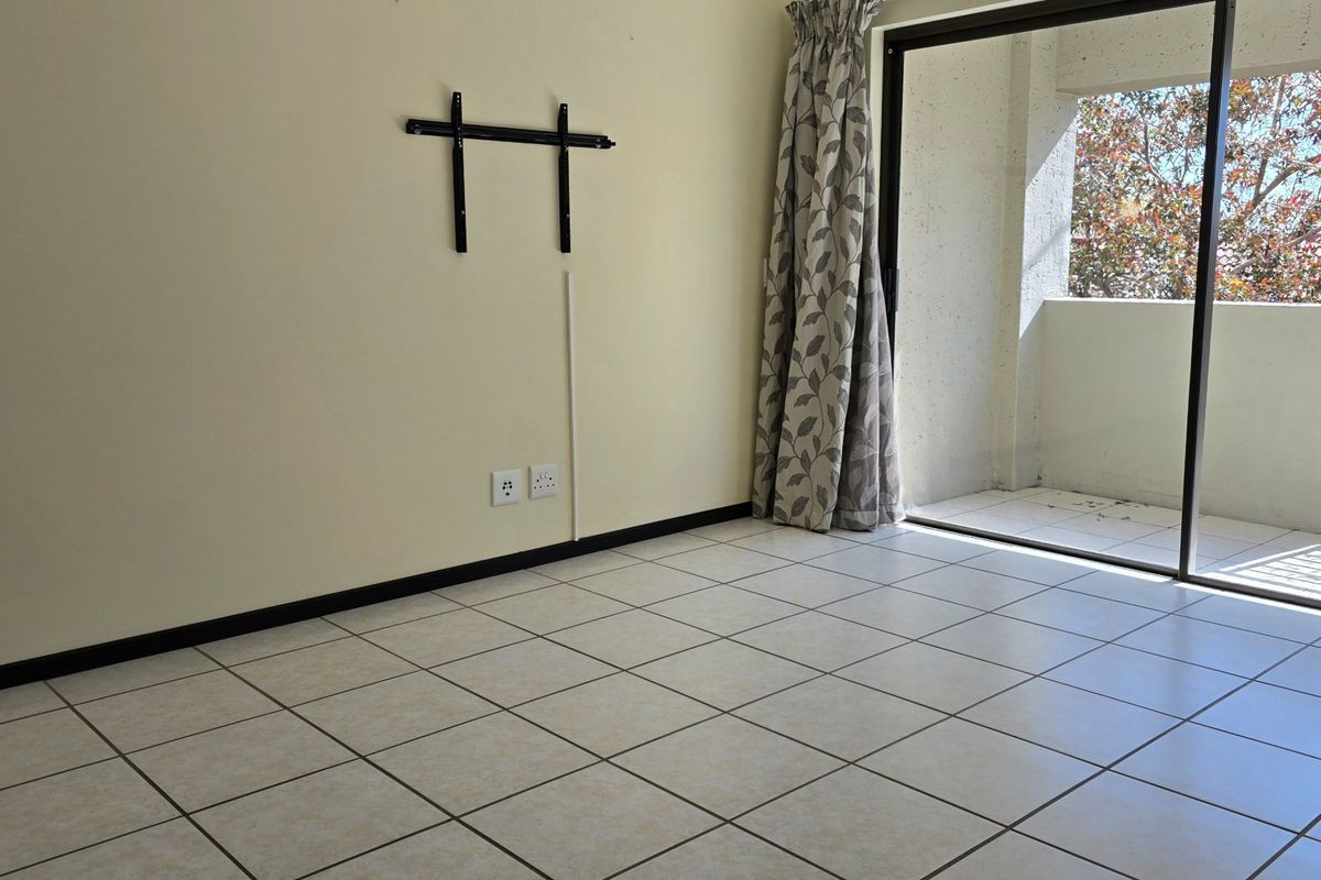 An empty living room featuring tiled flooring and a sliding glass door providing access to an outdoor balcony area.