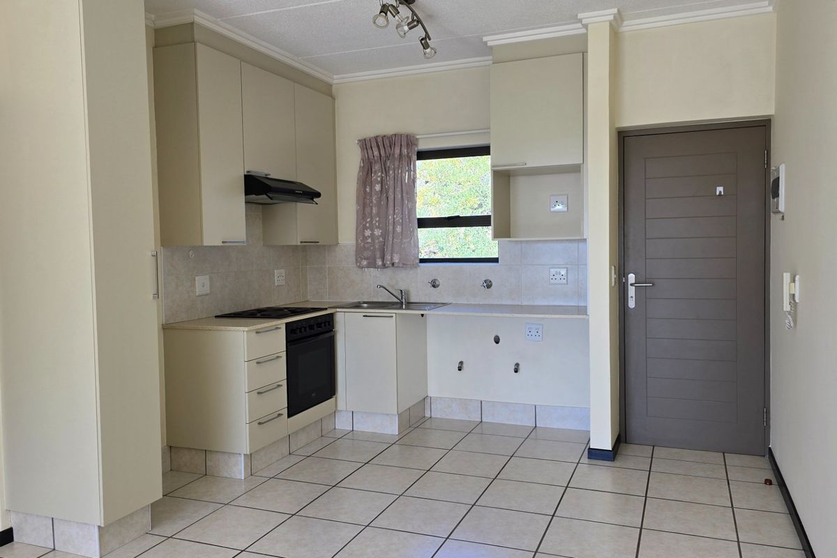 A functional kitchen featuring built-in cabinetry, an electric oven and hob, tiled flooring, and a tiled backsplash, ready for personalization.