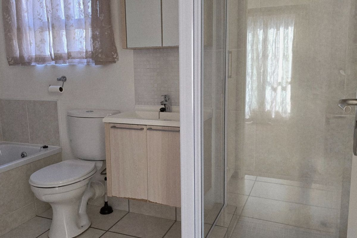 A functional bathroom featuring a bathtub, separate shower enclosure, toilet, and a vanity cabinet with a washbasin.