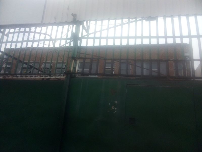 Exterior view of a commercial property featuring a brick facade secured by a metal gate and perimeter fencing.
